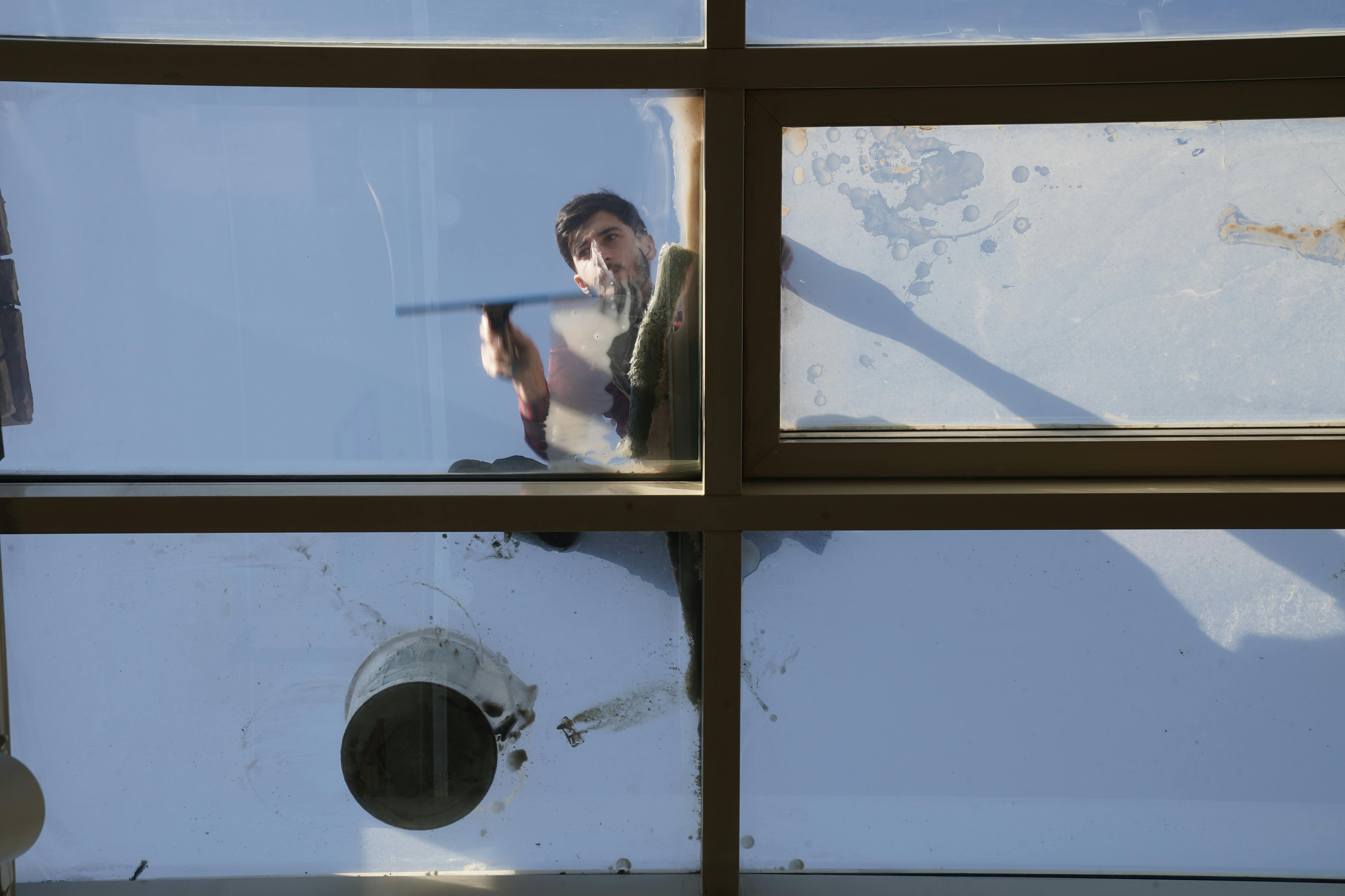Fensterputzer reinigt eine Glasfassade streifenfrei mit Abzieher